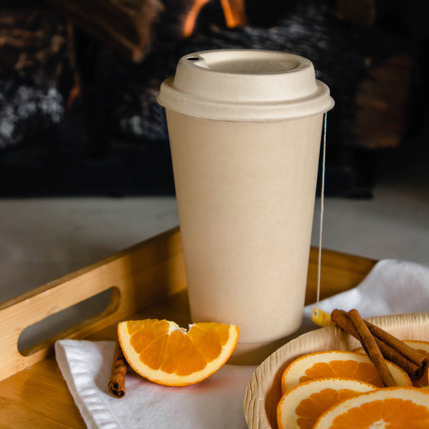 A 16oz compostable hot coffee cup with an orange slice and cinnamon sticks as decoration.