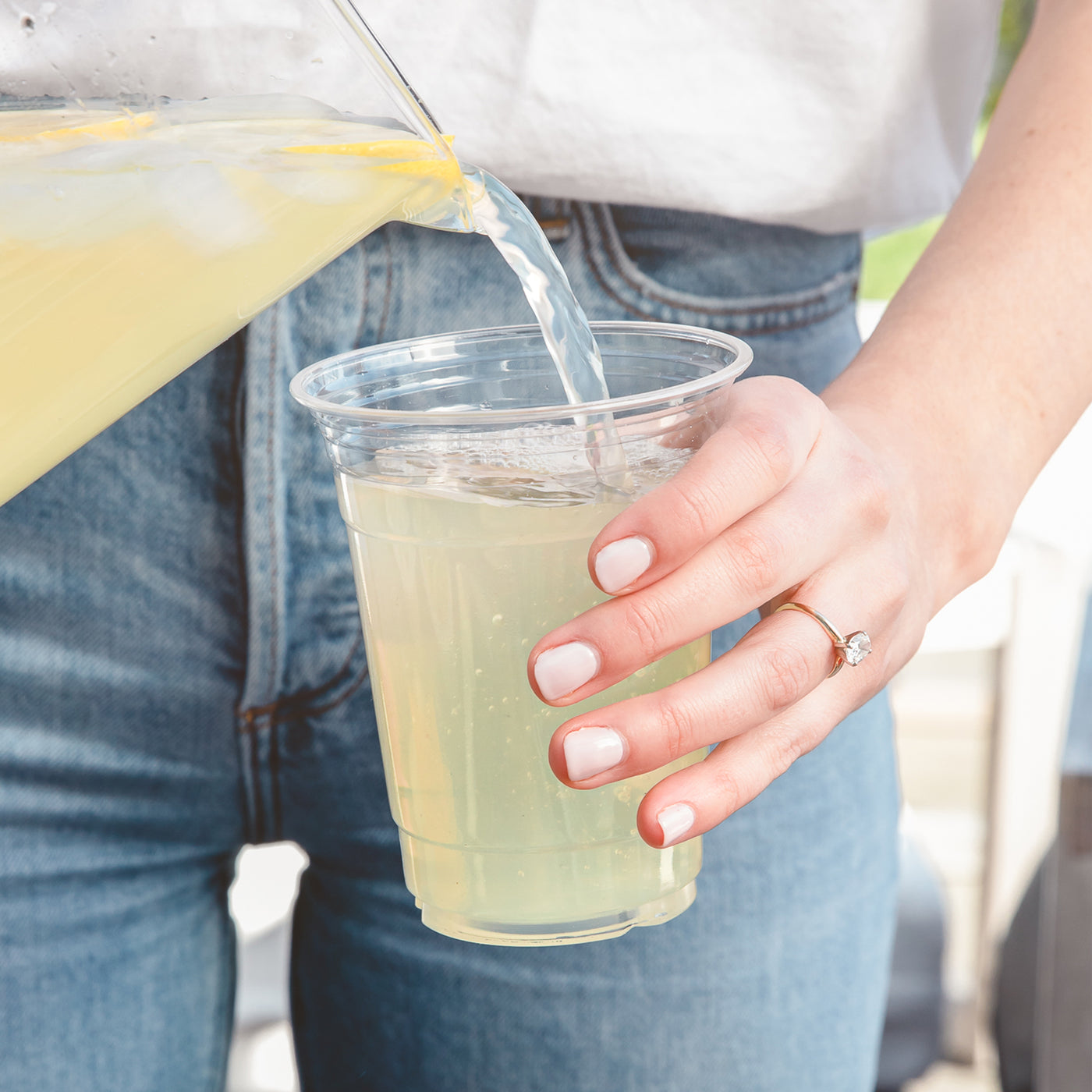 Refreshing lemonade being poured into a 12 oz compostable party cup.