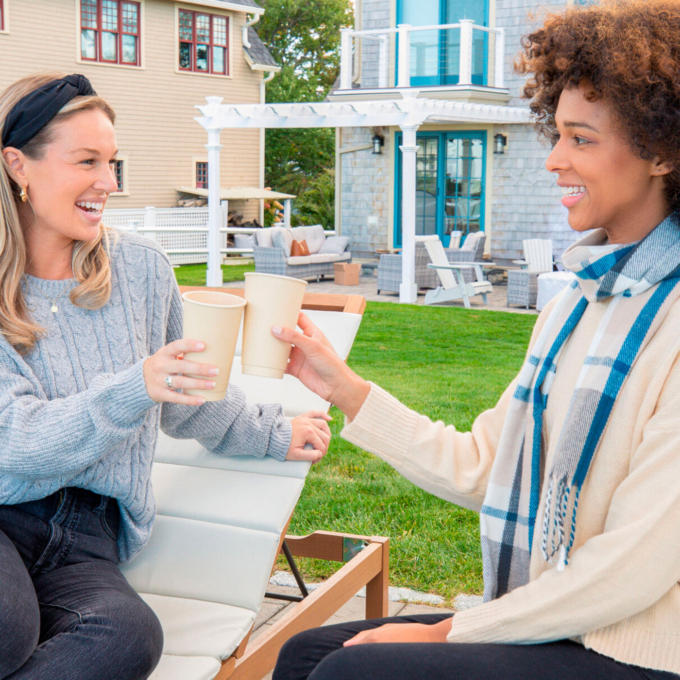 Two women having a conversation on a grassy field with a cup of drinks on 16oz Compostable Hot Cups Without Lids.