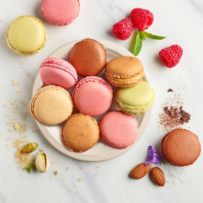 Macarons, raspberries, and nuts beautifully arranged on a 6-inch round compostable plate.