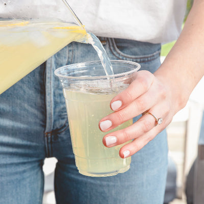 Woman pouring lemonade into a 16oz Compostable Party Cup.