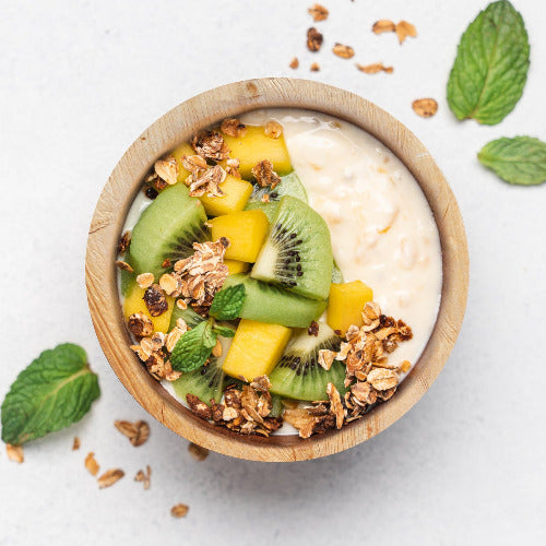 Yogurt with fruit and granola in a bowl on a white background. Served in a 16oz compostable 6-inch round palm leaf bowl.